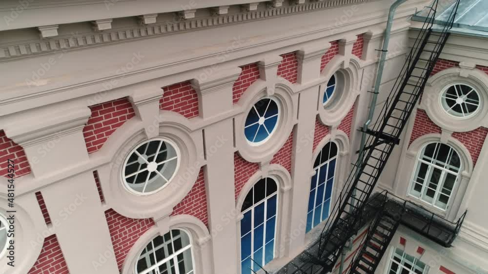 Vintage red brick building with white ornate and round windows equipped ...