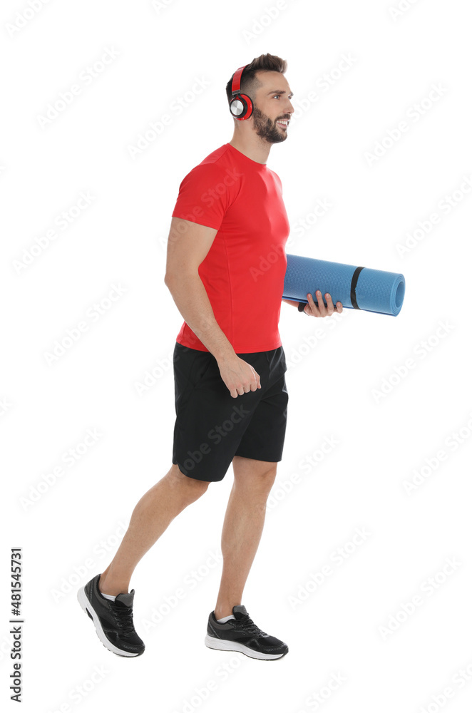Handsome man with yoga mat and headphones on white background