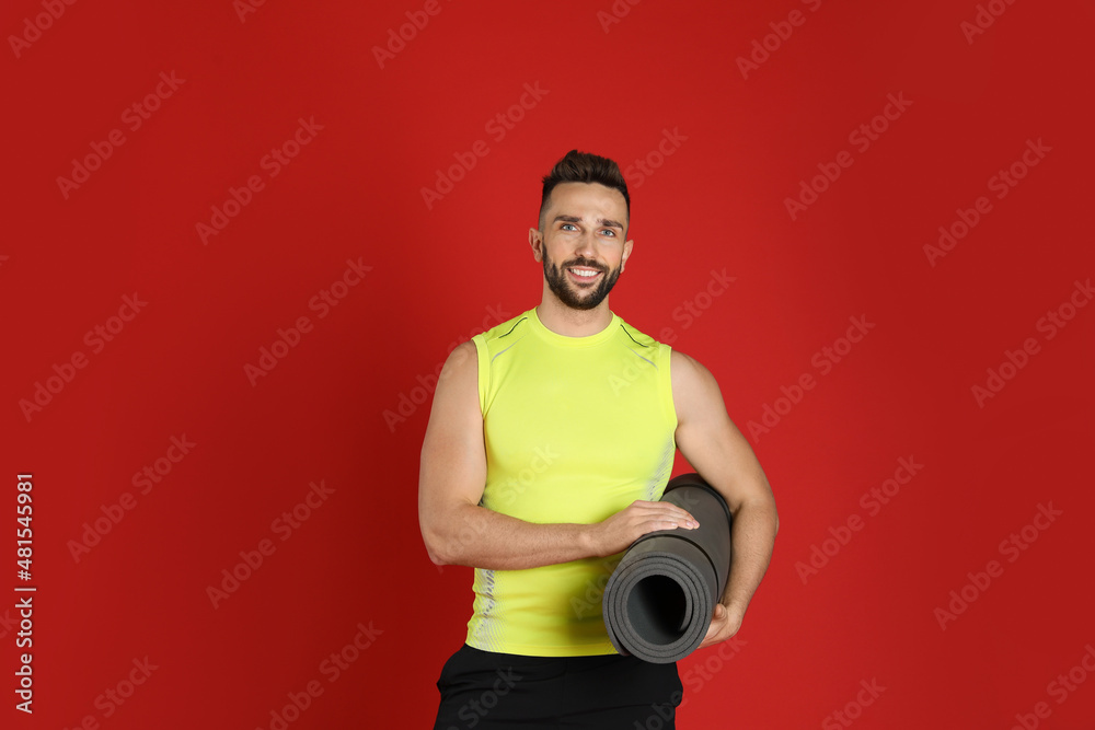 Handsome man with yoga mat on red background Handsome man with yoga mat on red background
