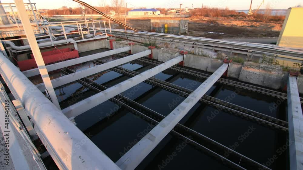 Large basins with dark water and bridge at contemporary waster water treatment station at sunset on winter day Large basins with dark water and bridge at contemporary waster water treatment station at sunset on winter day
