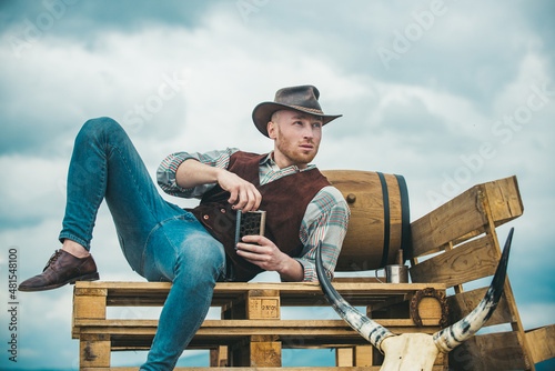 Sexy western man with cowboy hat. Attractive man with whiskey or brandy.