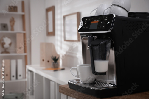 Fotografering Modern coffee machine with cup in office. Space for text