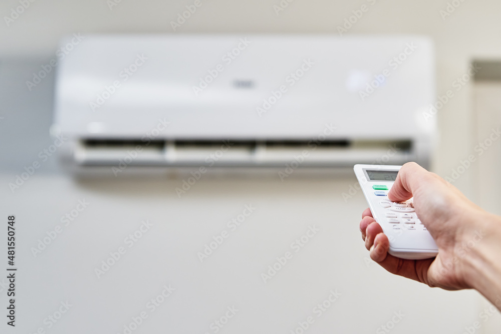 Fototapeta premium Hand adjusting temperature on air conditioner