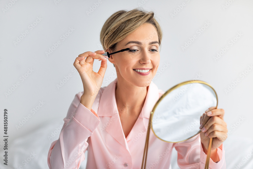 Closeup of smiling woman holding mascara applying makeup Closeup of smiling woman holding mascara applying makeup