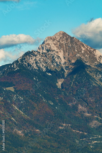 Alpine peak in the autumn on blue sky with clouds