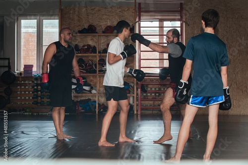 The coach conducts sparring between teenage boxers, shows the technique of hitting in boxing. Healthy active sports life concept