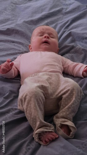 Sneezing caucasian baby lying on bed.
