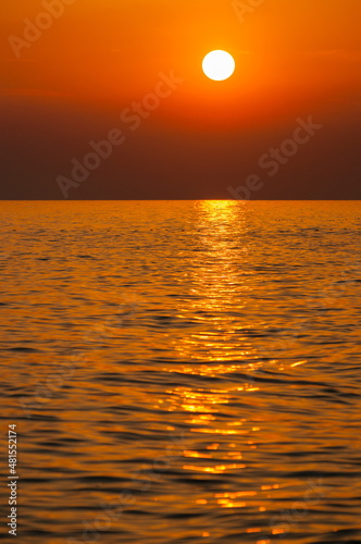 Golden hour sunset over sea with highly bright and clear orange sky