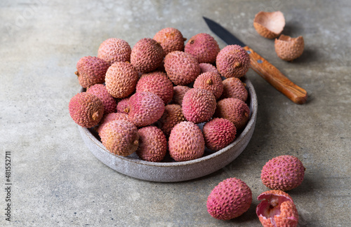 Fresh lychee fruit in plate on grey background. Copy space