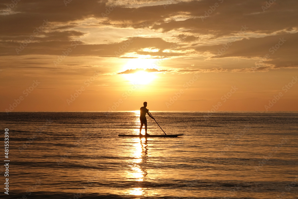 Man on paddle board and sub board floats on the ocean sea. Healthy lifestyle concept, water sports. Beautiful sunset on the beach                   