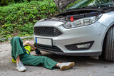 female mechanic in uniform trying to repair auto which broke down