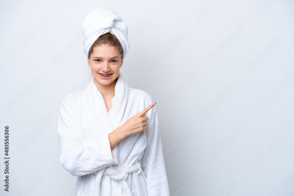 Teenager Russian girl in a bathrobe isolated on white background pointing to the side to present a product Teenager Russian girl in a bathrobe isolated on white background pointing to the side to present a product