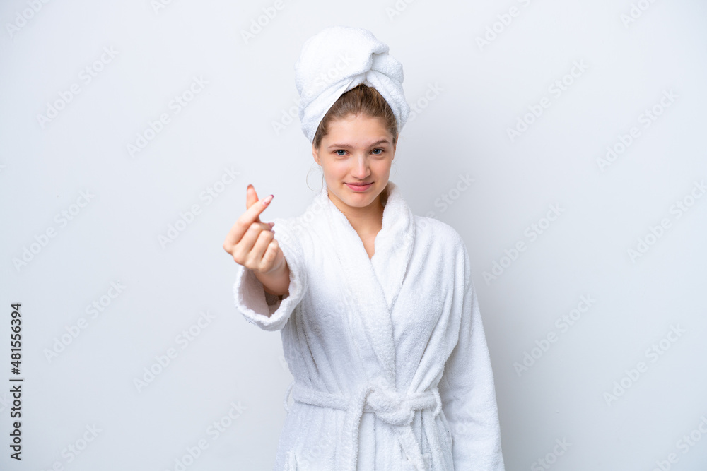 Teenager Russian girl in a bathrobe isolated on white background making money gesture Teenager Russian girl in a bathrobe isolated on white background making money gesture