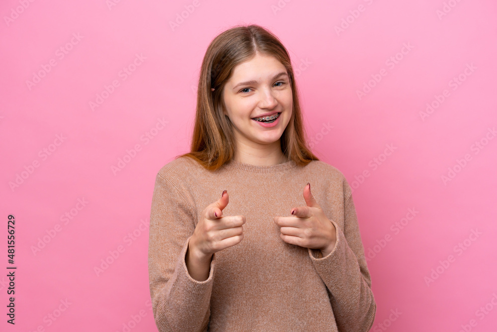 Teenager Russian girl isolated on pink background surprised and pointing front Teenager Russian girl isolated on pink background surprised and pointing front