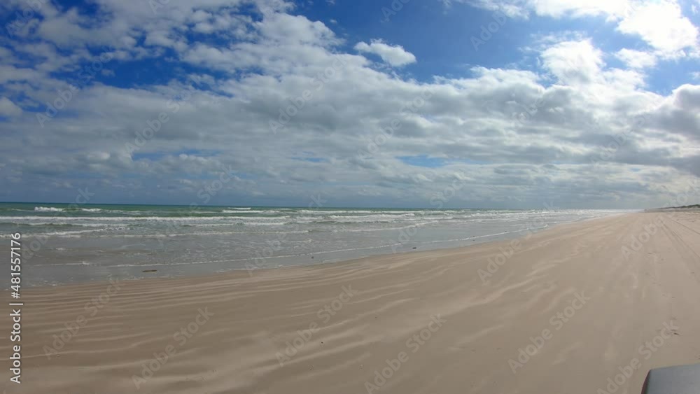 POV of a driving vehicle on the beach on North Padre Island National Seashore near Corpus Christi Texas USA on a partially cloudy day at low tide; concept of vacation, beach and weather POV of a driving vehicle on the beach on North Padre Island National Seashore near Corpus Christi Texas USA on a partially cloudy day at low tide; concept of vacation, beach and weather