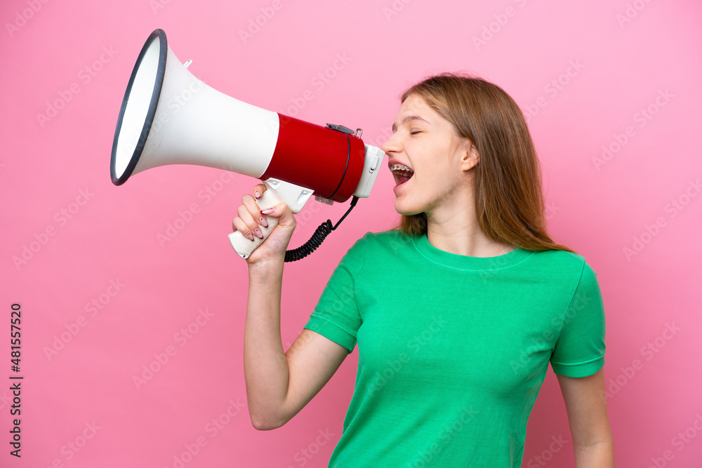Teenager Russian girl isolated on pink background shouting through a megaphone to announce something in lateral position Teenager Russian girl isolated on pink background shouting through a megaphone to announce something in lateral position