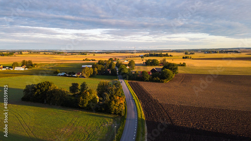 Aerial panorama of Swedish countryside, Swedish village at sunrise, clear blue sky, green yellow fields. View of typical landscape of southern Sweden. 