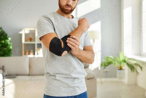 Foto Man wears bandage on his elbow which serves as fixator to restore and relieve joint pain