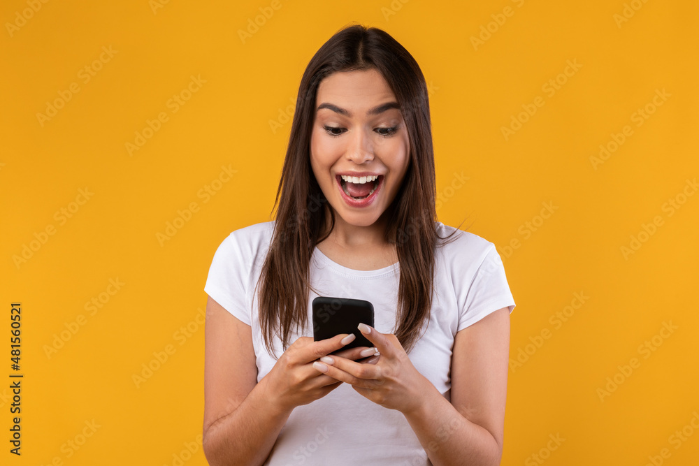 Happy excited lady using mobile phone at studio Happy excited lady using mobile phone at studio
