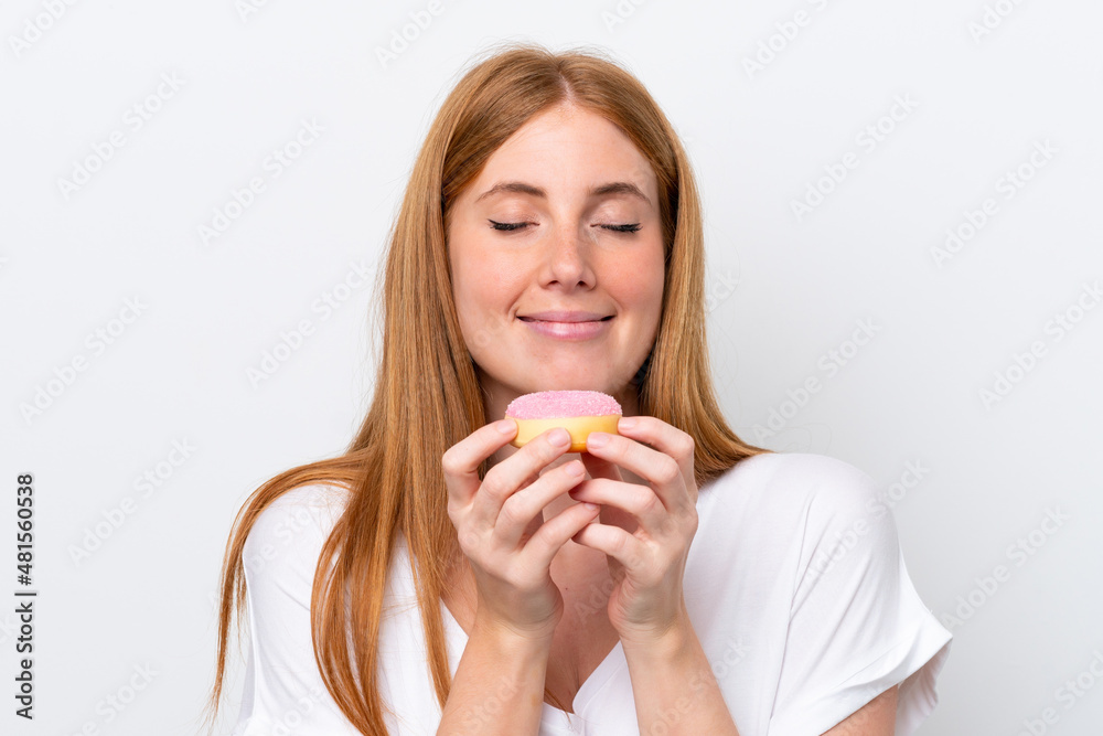 Young redhead woman isolated on white background holding a donut