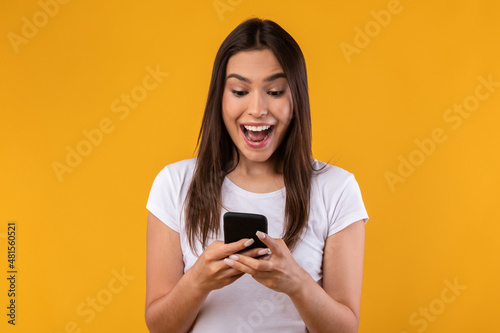 Happy excited lady using mobile phone at studio
