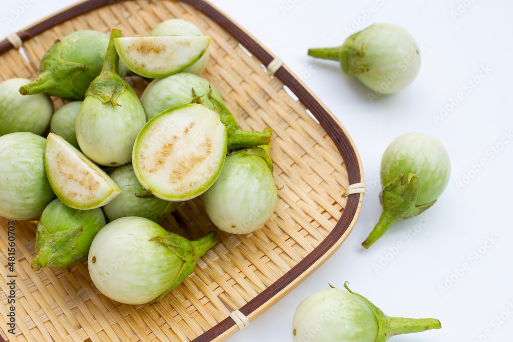 Organic green eggplant in bamboo basket on white background Organic green eggplant in bamboo basket on white background