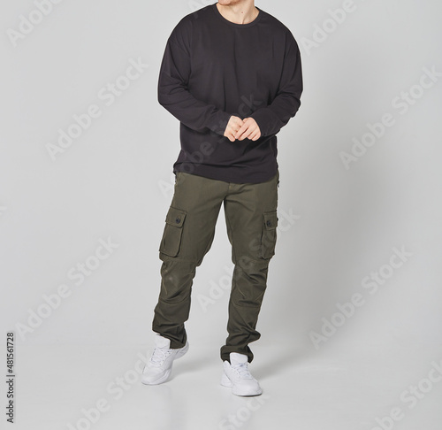 Cropped shot of man in black blank long sleeved and green cargo pants. Standing on gray background. Mockup for print or design template. Basic clothing line no logo