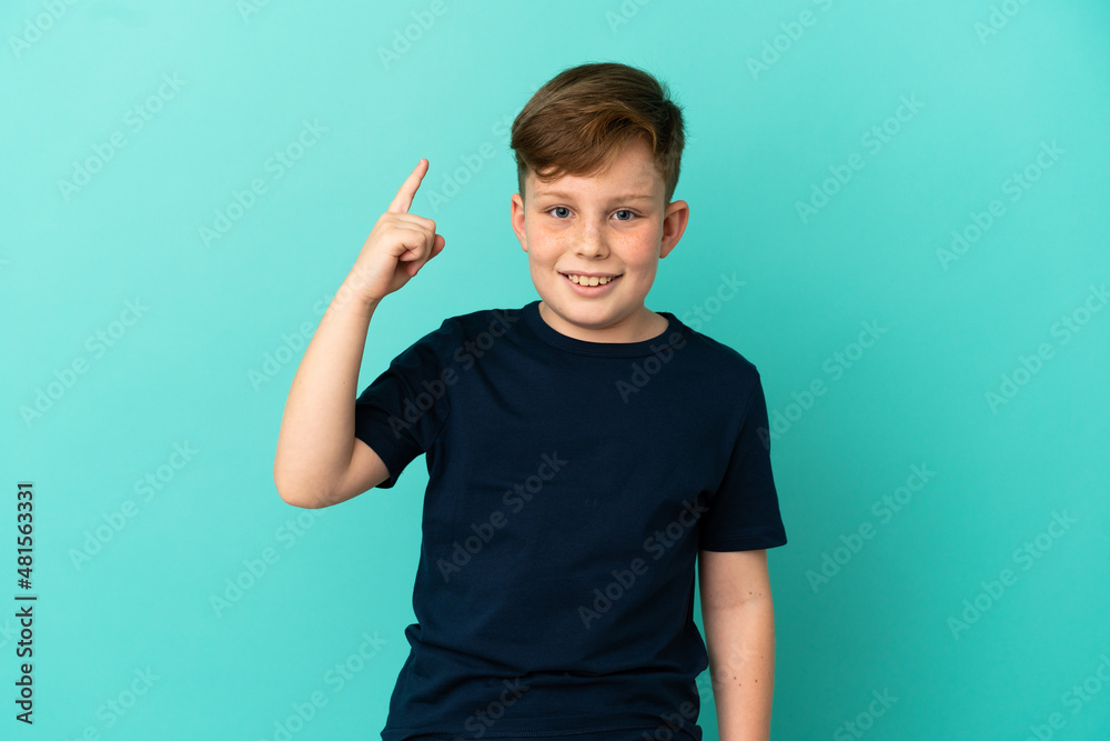 Little redhead boy isolated on blue background intending to realizes the solution while lifting a finger up Little redhead boy isolated on blue background intending to realizes the solution while lifting a finger up