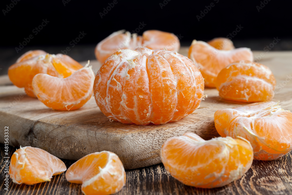 peeled ripe juicy tangerine on a wooden table