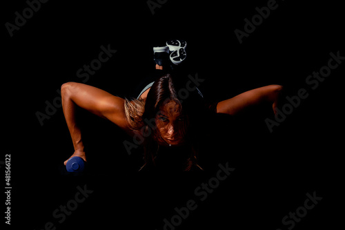 Fototapeta Naklejka Na Ścianę i Meble -  Brutal athletic woman pumping up muscles with dumbbells. Sexy attractive fitness woman, trained female body, lifestyle portrait, caucasian model.
