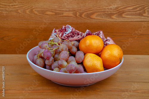 Delicious grapes and oranges. they are in a round vase. for a festive table. great pitch. fruit in a plate. on a wooden background. top view. close-up. food. photo