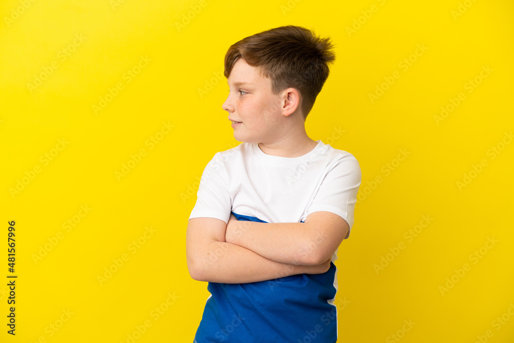 Little redhead boy isolated on yellow background with arms crossed and happy Little redhead boy isolated on yellow background with arms crossed and happy