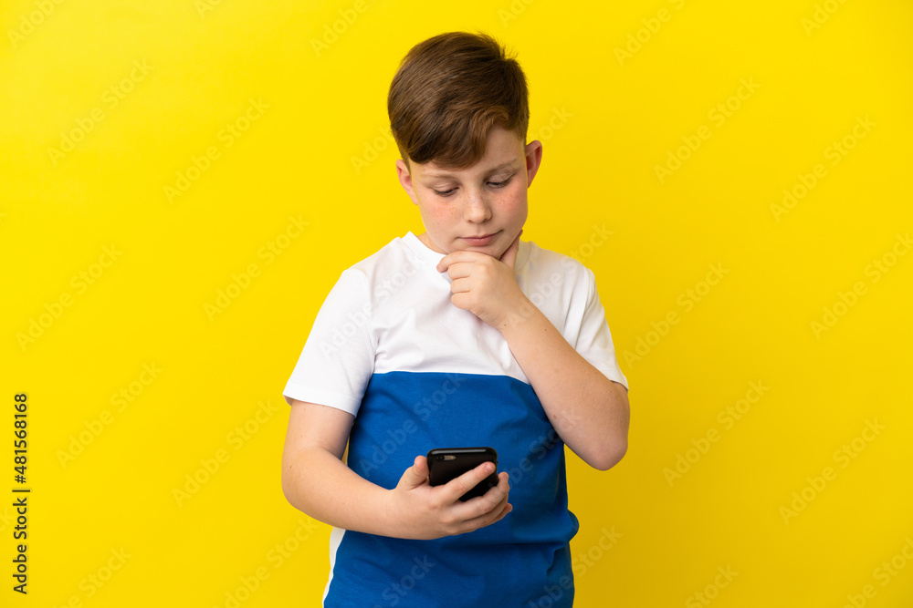 Little redhead boy isolated on yellow background thinking and sending a message Little redhead boy isolated on yellow background thinking and sending a message