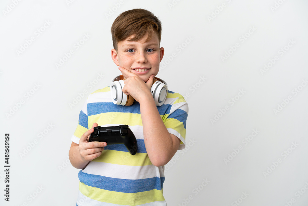 Little redhead boy holding a game pad isolated on white background happy and smiling Little redhead boy holding a game pad isolated on white background happy and smiling