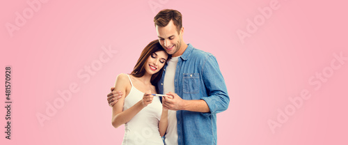 Love, relationship, new parents and happy family concept - young couple, finding out results of a pregnancy test, isolated on pink background. Copy space for some text.