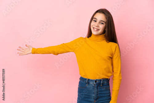 Little girl isolated on pink background extending hands to the side for inviting to come