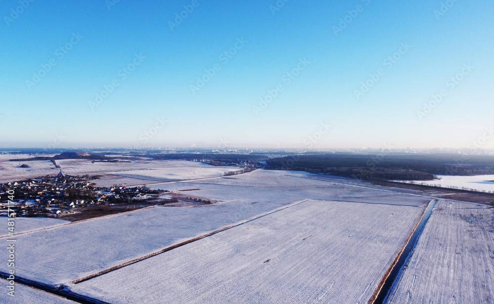 View from a height of a large winter landscape with a snowy field of the suburbs View from a height of a large winter landscape with a snowy field of the suburbs