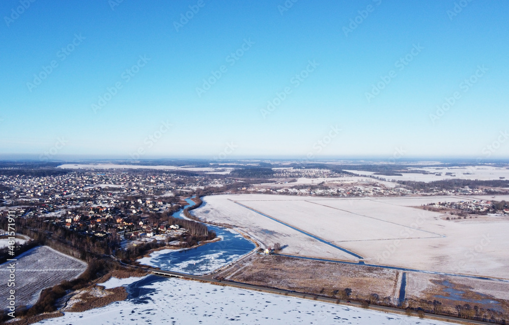 View from a height of a large winter landscape with a snowy field of the suburbs