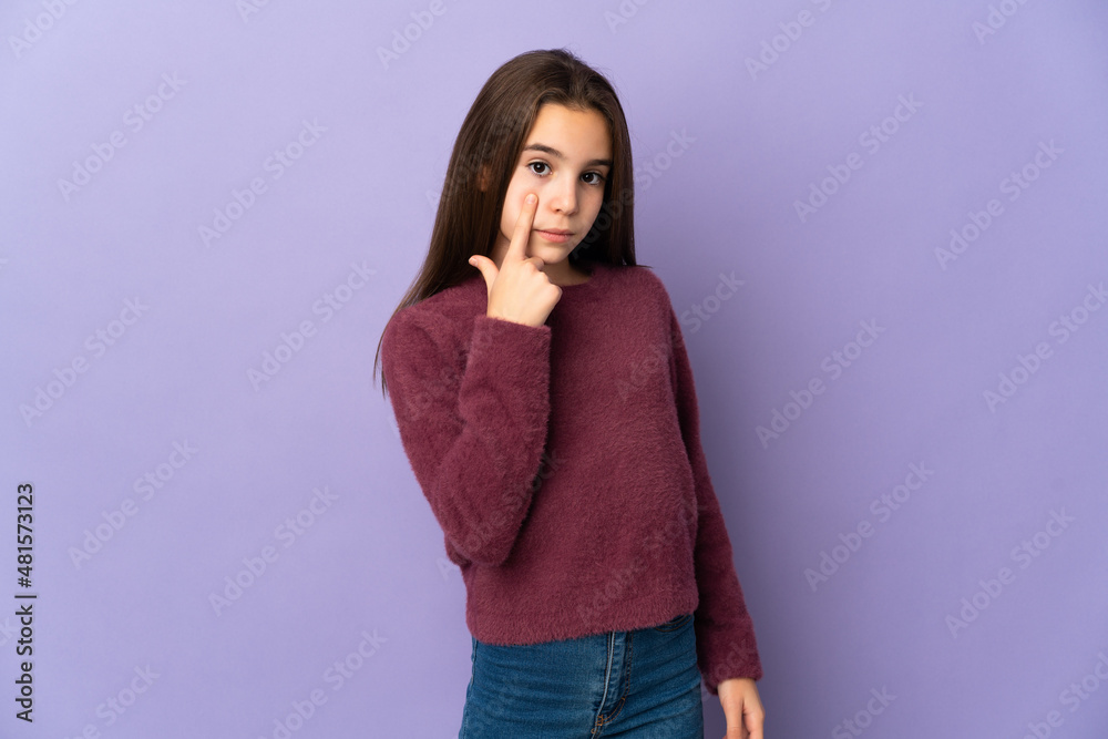 Little girl isolated on purple background showing something
