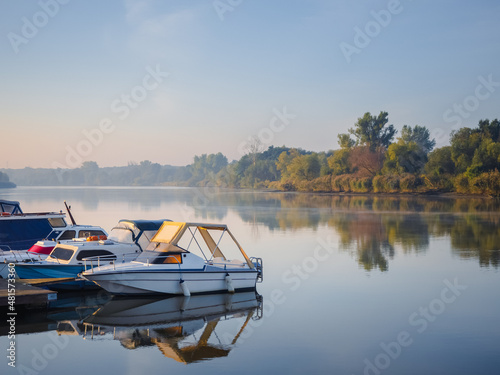 Fototapeta moored motorboats on a pier on a river in a early summer morning