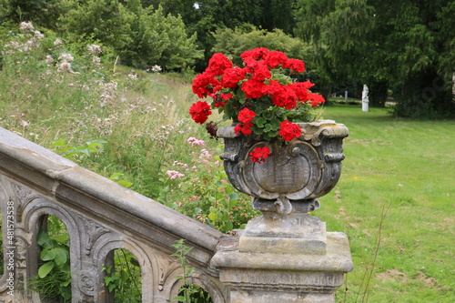 Blumenkübel Barock mit roten Blumen an Treppe zu antikem Gebäude im Kurpark Bad Nenndorf