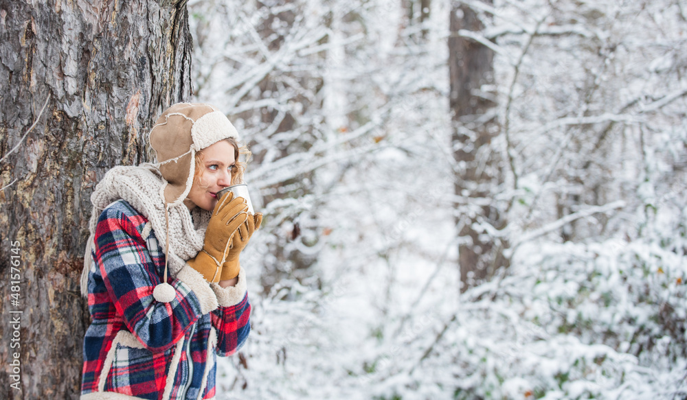 woman winter drink. Girl enjoy snow fall. woman in mittens and hat drinking tea in snowy forest. outdoors on frosty day. travel and hiking. girl hiker drink cup of hot tea. warm yourself up woman winter drink. Girl enjoy snow fall. woman in mittens and hat drinking tea in snowy forest. outdoors on frosty day. travel and hiking. girl hiker drink cup of hot tea. warm yourself up