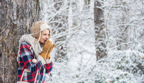 woman winter drink. Girl enjoy snow fall. woman in mittens and hat drinking tea in snowy forest. outdoors on frosty day. travel and hiking. girl hiker drink cup of hot tea. warm yourself up © be free