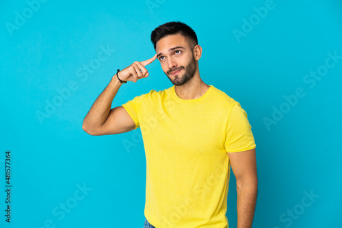 Young caucasian man isolated on blue background making the gesture of madness putting finger on the head