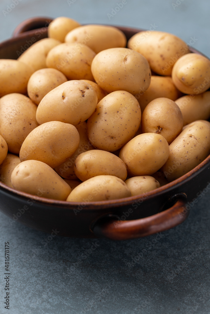 Raw small potatoes in a cast iron skillet on a beton background. Raw small potatoes in a cast iron skillet on a beton background.