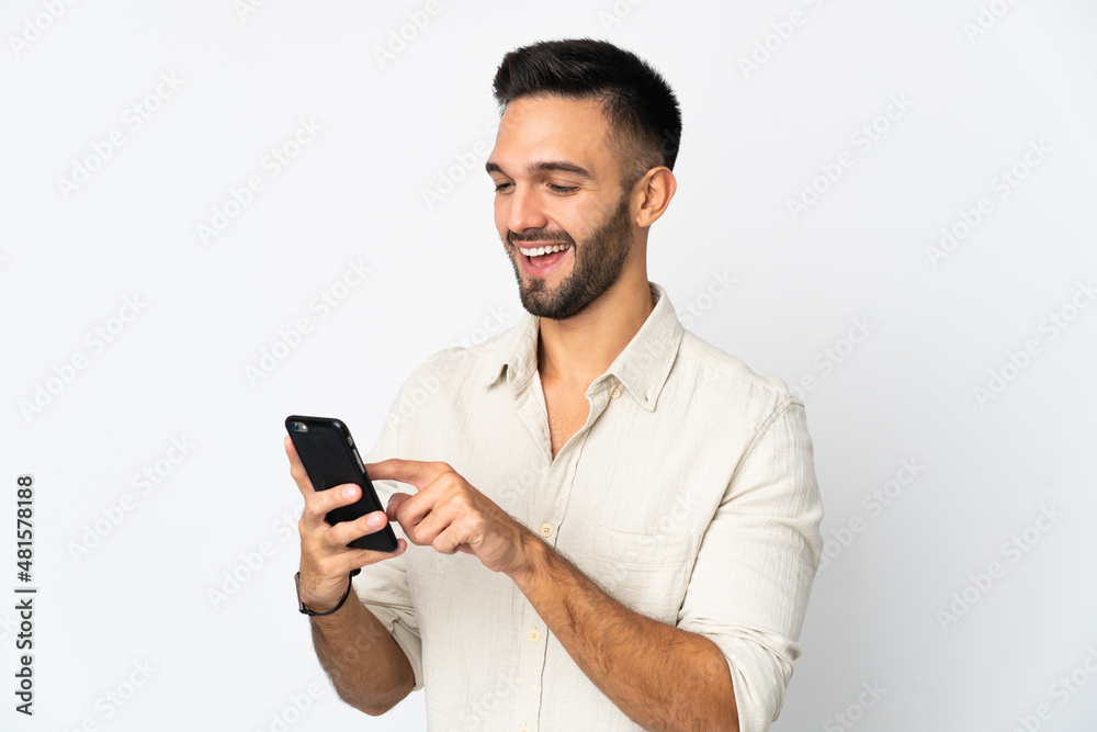 Young caucasian man isolated on white background sending a message or email with the mobile Young caucasian man isolated on white background sending a message or email with the mobile