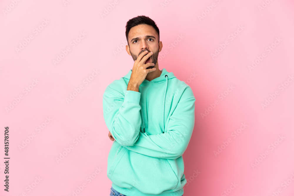 Young caucasian man isolated on pink background surprised and shocked while looking right