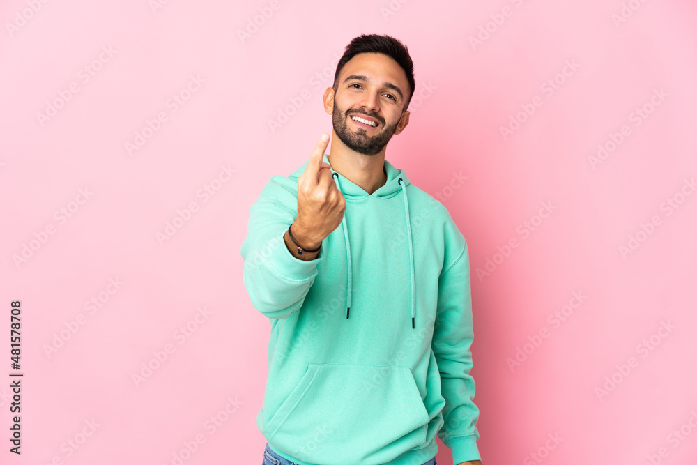 Young caucasian man isolated on pink background doing coming gesture Young caucasian man isolated on pink background doing coming gesture