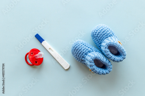 Baby boy booties with pregnancy test. Morherhood and pregnancy concept