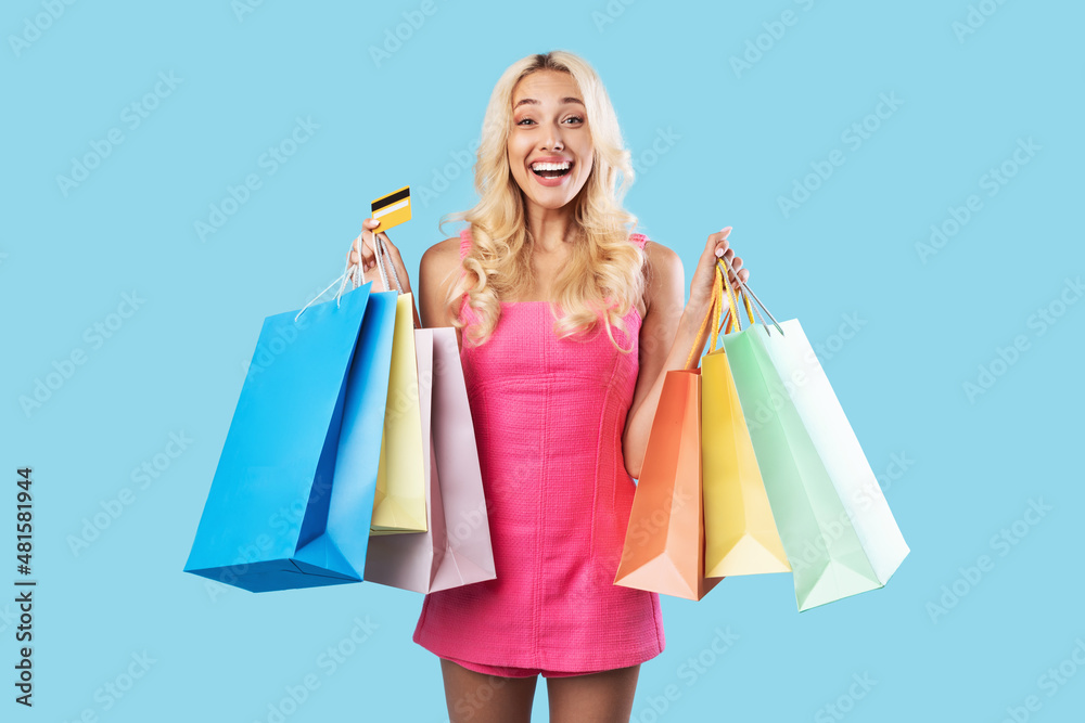 Happy woman holding credit card carrying shopping bags